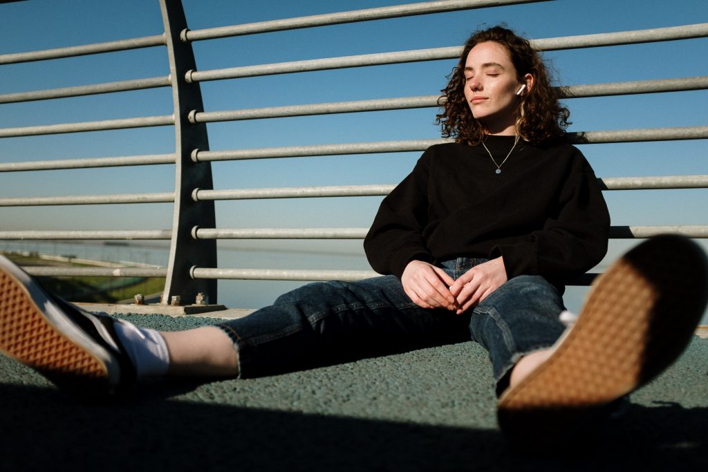 A woman sitting on the road wearing replica sneakers